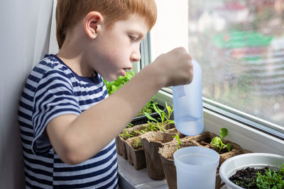 Side view of young woman holding potted plant