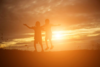 Silhouette friends standing against sky during sunset