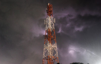 Low angle view of illuminated communications tower against sky at night