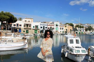 Portrait of young woman moored at harbor against sky