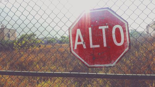 Information sign on chainlink fence against sky