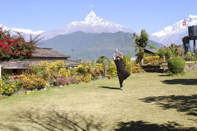 Woman standing by flowers against mountain