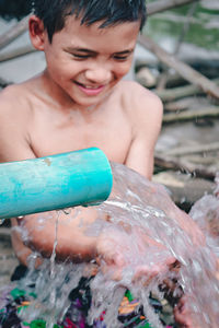 Full length of shirtless boy holding water