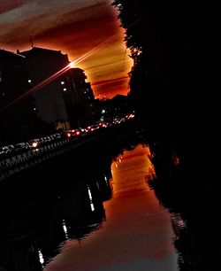 Illuminated bridge over river against sky at sunset