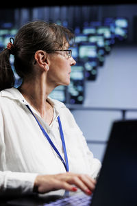 Side view of woman using laptop at office