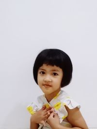 Portrait of cute girl with arms crossed against white background