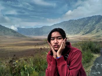 Portrait of woman with hands on cheek standing against plants