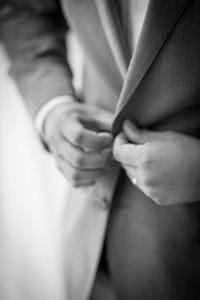 Midsection of man buttoning suit