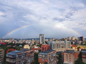 Rainbow over cityscape against sky