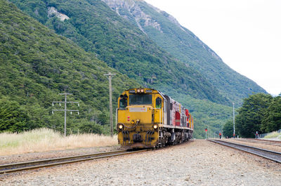 Train by green mountain against sky