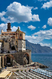 Buildings by sea against sky