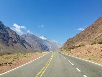 Road leading towards mountains against sky