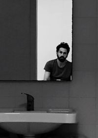 Reflection of man on mirror in bathroom