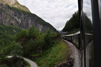 Panoramic view of train by mountains against sky