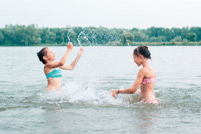 Two cheerful girls play with splashes in the river. local tourism. summer vacation
