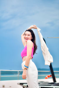 Portrait of young woman standing against swimming pool