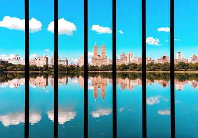 Reflection of buildings in reservoir against blue sky