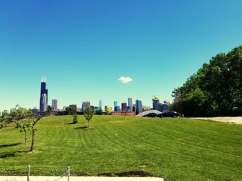 Scenic view of field by buildings against clear sky