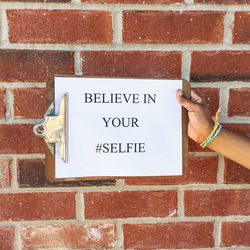 Cropped image of person holding clipboard with text against brick wall