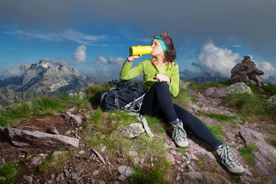 Man photographing on rock against sky