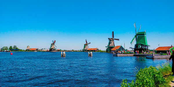 Cranes by sea against clear blue sky