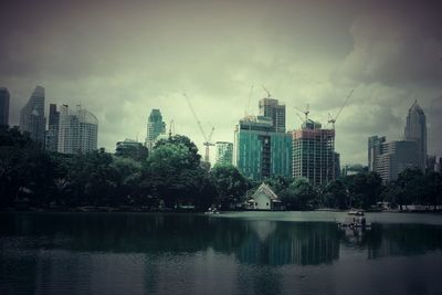 City buildings by lake against sky