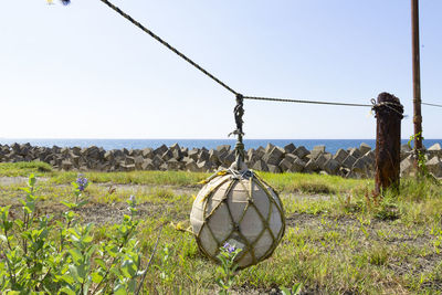 Traditional windmill on field by sea against clear sky