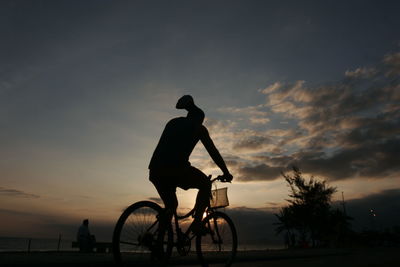 Silhouette man riding bicycle against sky during sunset