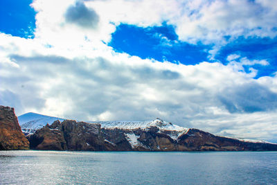 Scenic view of sea and mountains against cloudy sky