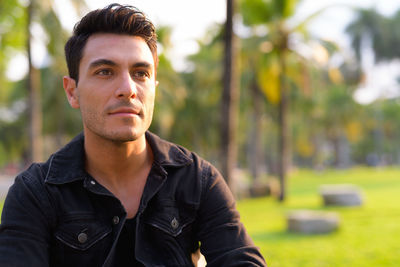 Smiling man looking away while standing at park