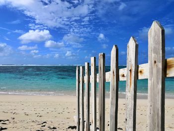 Wooden posts on beach against sky