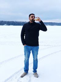 Portrait of man having drink on snowy field