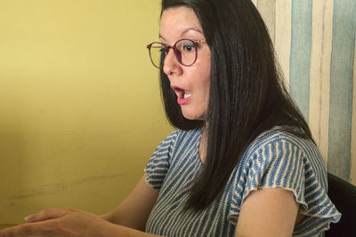 Portrait of woman sitting against wall