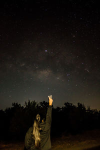 Woman with arms raised against sky at night
