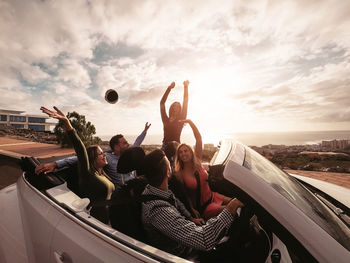 Cheerful friends having fun on road trip during sunset