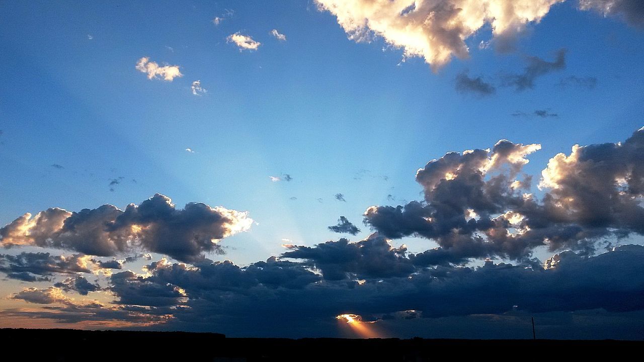 sky, scenics, beauty in nature, cloud - sky, silhouette, tranquil scene, blue, tranquility, nature, low angle view, sunbeam, idyllic, cloud, sunlight, sunset, sun, outdoors, cloudy, dusk, no people