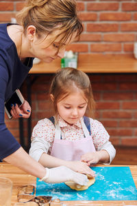 Cute girl and mother cooking food at kitchen