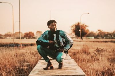 Full length portrait of smiling boy on landscape against sky during sunset