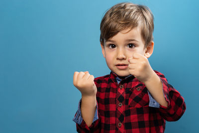 Portrait of cute boy standing against blue background