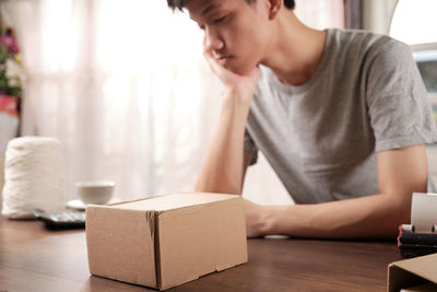 Sad man with box on table sitting on sofa at home