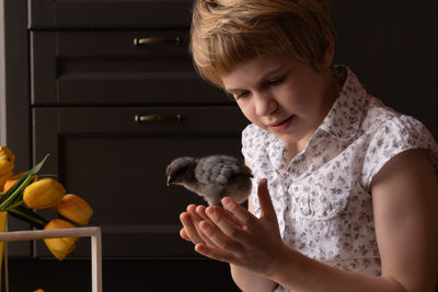 Girl holding chicken bird at home