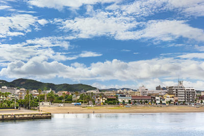 Buildings by river against sky in town