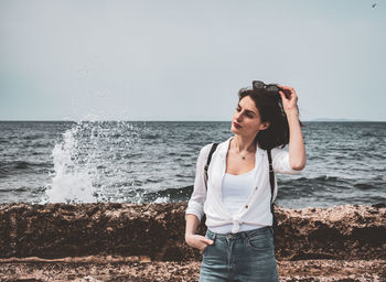 Young man standing on sea shore against sky