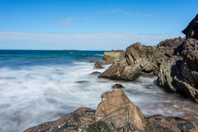 Scenic view of rocks on beach against sky