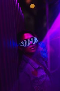 Portrait of woman wearing illuminated sunglasses at nightclub