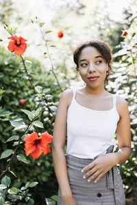 Portrait of young woman standing amidst flowers