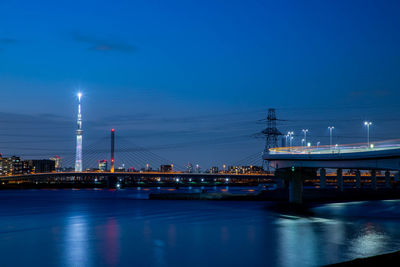 Illuminated bridge over river against sky at night