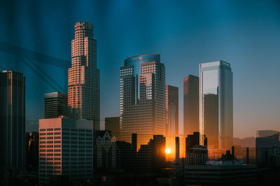 Modern buildings in city against sky at dusk