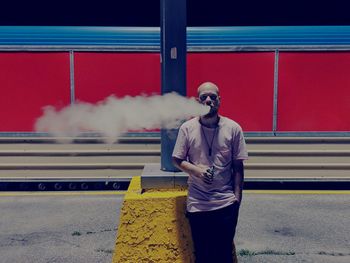 Man smoking electronic cigarette while standing at railroad station platform