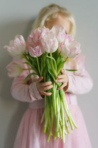 Little girl holding a bouquet of pink tulips.